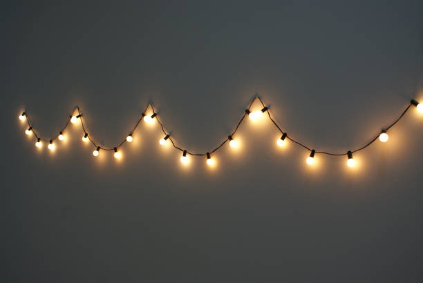 istock Yellow bulbs garland hanging on the grey wall. 1673664392