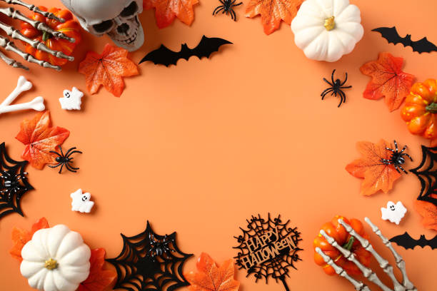 istock Halloween frame with decorations, pumpkins, spiders, bats, skull, maple leaves on pastel orange background. Top view with copy space, flat lay. 1673667026