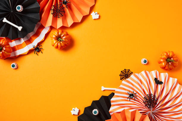istock Happy Halloween holiday concept. Flat lay composition with Halloween decorations, folding paper fans, pumpkins, bones, bloody eyes, spider webs, ghosts on orange background. 1673686859