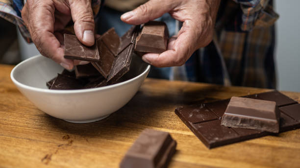 Human hands breaking chocolate Close-up of man's hands breaking piece of chocolate. man hand holding candy bar stock pictures, royalty-free photos & images