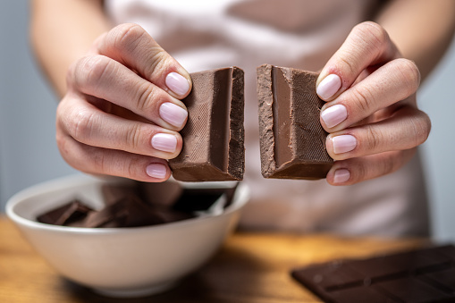 Close-up of woman's hands breaking piece of chocolate.