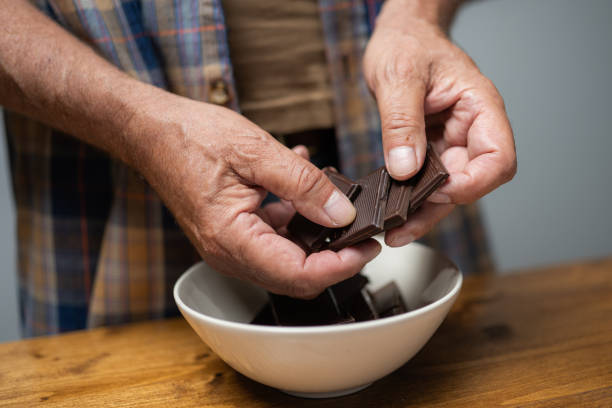 Human hands breaking chocolate Close-up of man's hands breaking piece of chocolate. man hand holding candy bar stock pictures, royalty-free photos & images