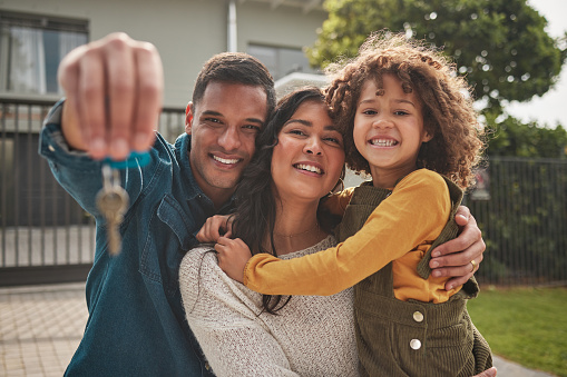 Happy family, portrait and real estate with keys in property, investment or new home together. Mother, father and child smile in relocation, buying or mortgage loan in building, finance or investing