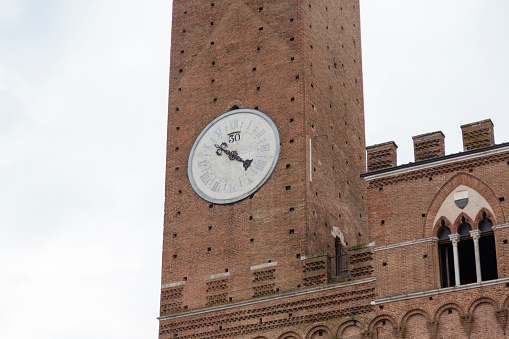 Brunico, Italy – September 13, 2023: A towering clock structure adjacent to a slope-side building