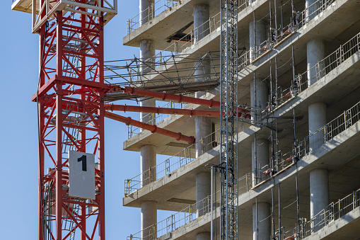 High-rise construction site with fixed construction crane on reinforced concrete skeleton construction