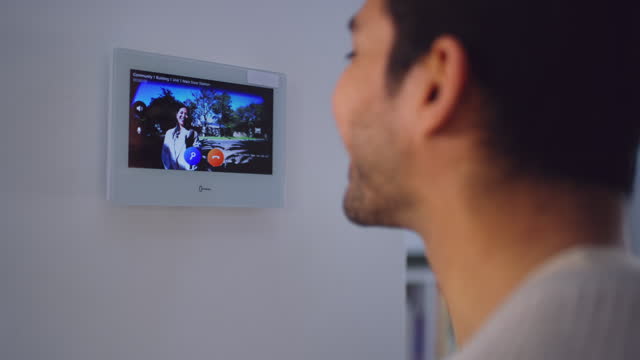 Man, intercom and video in home for security, check and access code to home, talking and welcome. Guy, monitor and conversation with screen for safety, technology and communication with wave at house