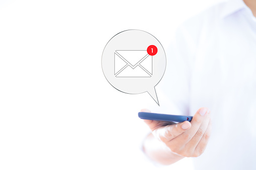 Businessman's hand and email icon showing on smartphone email marketing ideas Companies send mass emails or digital newsletters to customers.