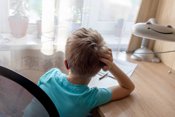 istock unrecognizable first-grade boy can't bring himself to do his homework, daydreaming while staring out window. Procrastination, school workload 1673800353