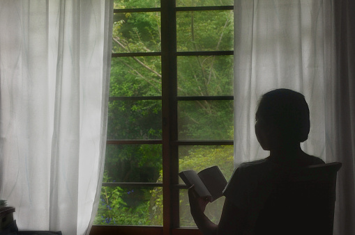 Woman Reading Book by the Window/in Back Light