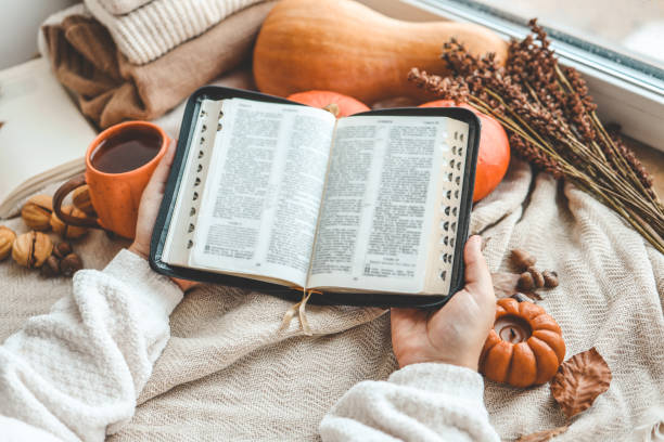istock Open Bible in female hands in autumn interior 1673818644