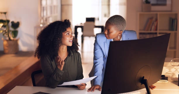 istock Paperwork, computer and business women at night working on project, deadline and planning in office. Collaboration, teamwork and workers in discussion for proposal, report and schedule in overtime 1673845780