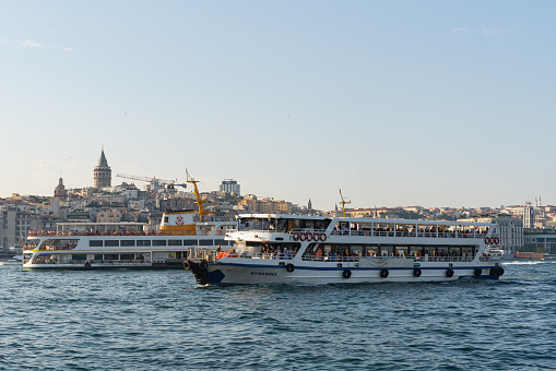 Istanbul, Turkey, June 6, 2023: Two ferries warm up with each other in the Bosphorus Strait against the background of the old city in the distance and the blue sky Strait between two continents