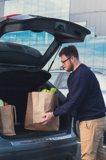 istock happy man put groceries bag in car trunk 1673859639