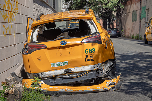 Crescent Street, Long Island City, Queens, New York, USA - August 19th 2023:  Broken yellow New York taxi abandoned in a side street