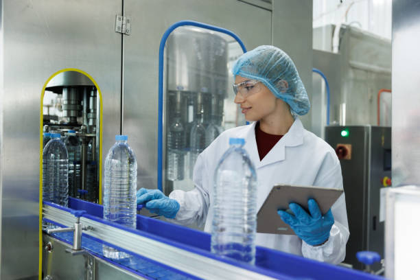 istock Water bottling line for processing and bottling pure mineral carbonated water into bottles. Female worker checking out water bottles 1673870086