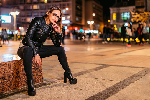 Beautiful young woman sitting in the town square.