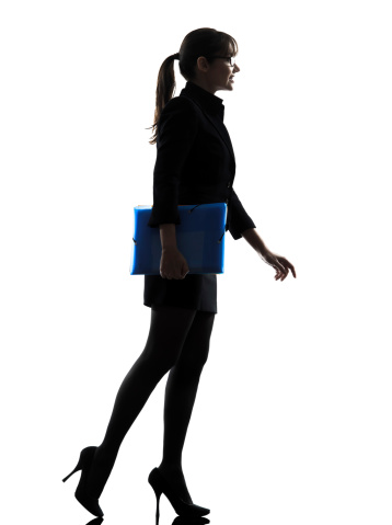 one caucasian business business woman holding folders files walking silhouette in silhouette studio on white background