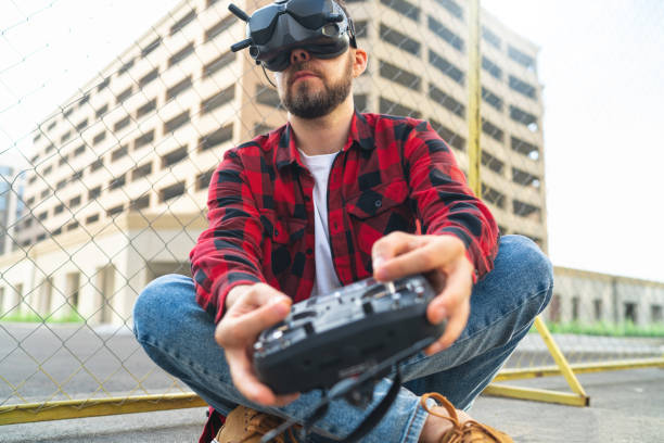 istock Close up portrait of casually dressed male fpv pilot operating drone using goggles nad remote controller 1673906898