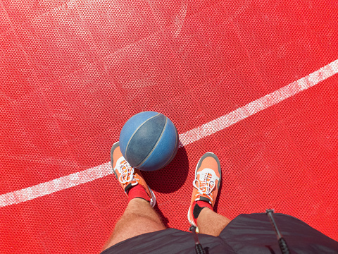 Basketball player with ball on a outdoor court.