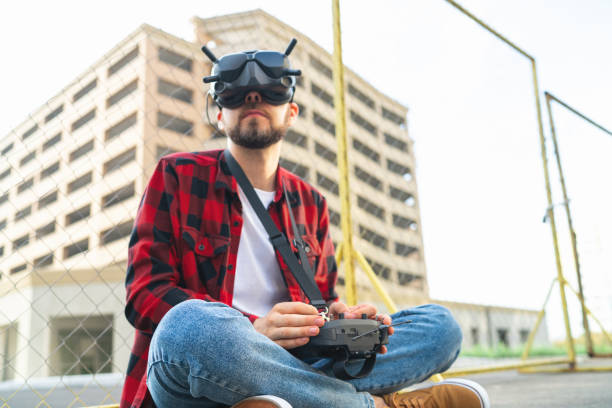 istock Male drone pilot operating fpv multicopter uisng goggles and remote controller for taking aerial urban photography and videography 1673908688