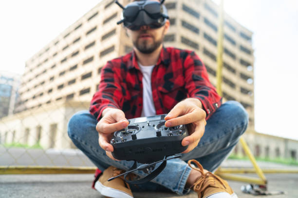 istock Outdoor portrait of casually dressed male fpv pilot operating multicopter drone using goggles nad remote controller 1673908696