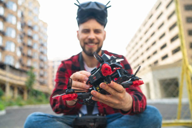istock Outdoor portrait of smiling casually dressed bearded man setting generic design fpv multicopter drone in his hands while sitting at the street 1673908788