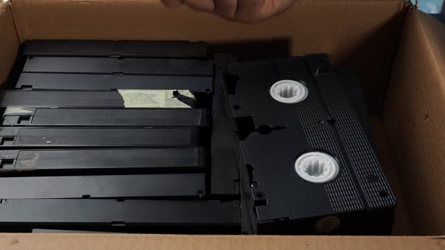 Old VHS tapes in a cardboard box.