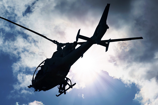 Silhouette of a combat helicopter in the sky, gazelle seen from underneath, air transportation