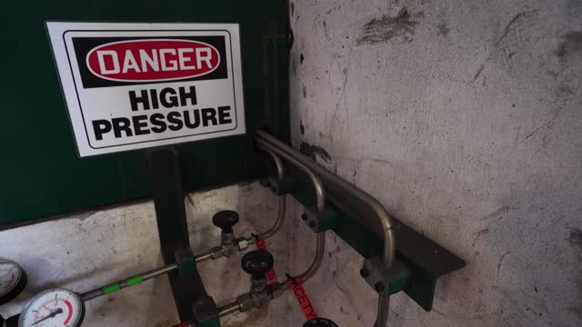 High Pressure sign on the wall above high pressure valve from Oxygen and Acetylene tanks, warning people for high pressure hazard.