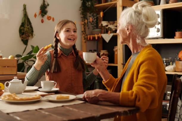 Cute smiling girl with pigtails telling something to her grandmother