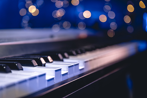 Close up of piano keys on blurred background with bokeh, music background.