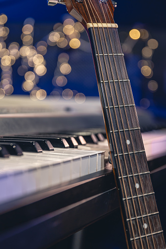 Guitar and piano keys close-up on a blurred background with bokeh, musical holiday background.