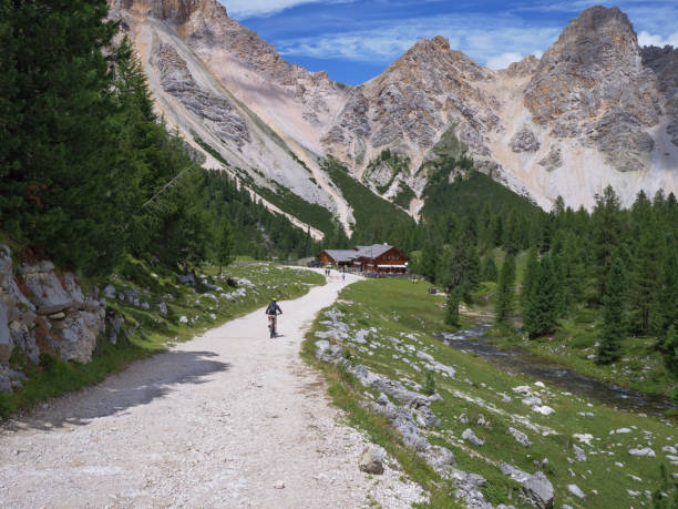 アルプスのルートの山の未舗装の道路で電動マウンテンバイクに乗る観光客、イタリア - footpath single lane road sunrise landscape ストックフォトと画像