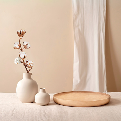 Beige ceramic vases with dry cotton branches. Stylish and minimalistic background for display your products in living room. Scandinavian interior. Modern home decor. Copy space.