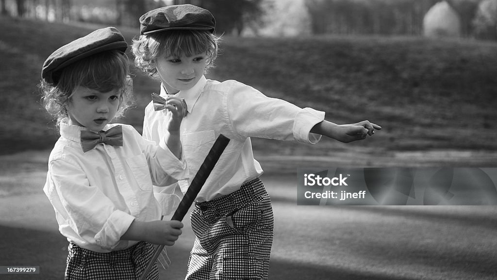 Giovani ragazzi a giocare a golf in vintage uniformi - Foto stock royalty-free di Abbigliamento elegante