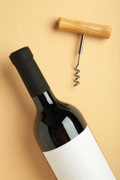 istock Bottle with red wine and corkscrew on beige background. Vertical photo 1673993868