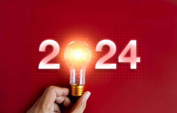 istock Shining 2024 calendar year numbers, neon style with creative trend light bulb holding by businessman's hand on digital network and red background. Happy 2024 New Year greeting card with light bulb. 1673996101