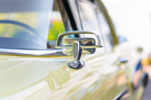 Vintage collector car amber-colored headlight in a chrome frame, close up, positioned upper left in a vertical composition, with the backdrop formed by the green and orange vehicle bodywork.
