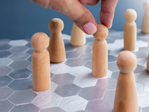 istock Leadership, human resource, hiring, selection, recruitment, business plan and strategy concepts. Businessman hand choosing the candidate of wooden human figures on hexagon pattern floor background. 1673996678