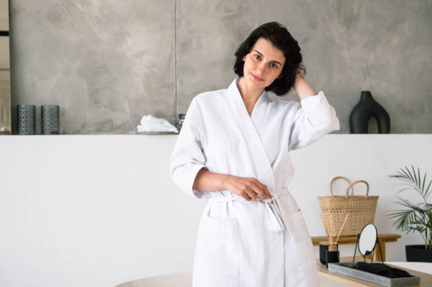 istock Young woman in white bathrobe standing in domestic bathroom 1673997946