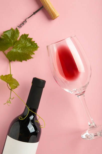 istock Wine bottle with wine glass and corkscrew lying on pink background. Vertical photo 1674004850