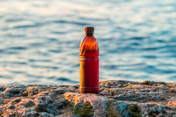 пиво в пластиковой бутылке на берегу - sand grains стоковые фото и изображения