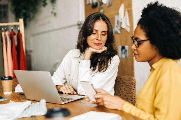 istock Two female clothing designers using a mobile phone together 1674009703