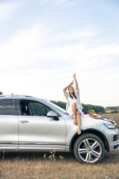 istock Attractive young woman sits on a car in a field. 1674010263