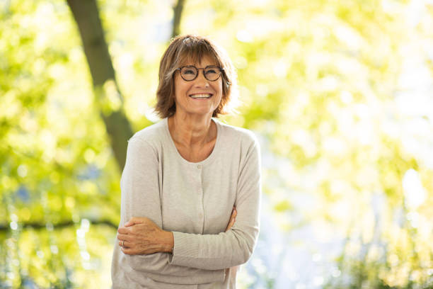 istock woman in 60s smiling outside in park 1674014761