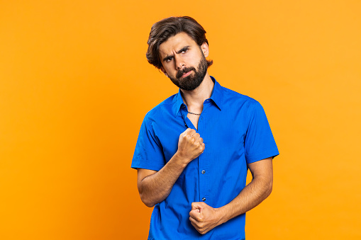 Irritated frustrated annoyed young middle eastern man raising hands in indignant expression, quarreling, asking reason of conflict, why such stubborn. Arabian guy isolated on orange studio background