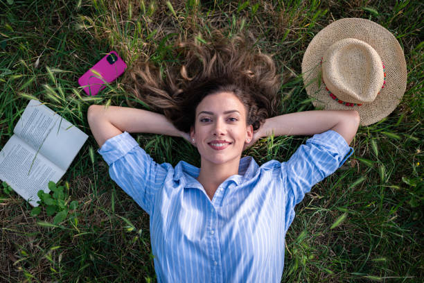 istock Young Caucasian woman, lying on the grass, relaxing while reading a book 1674018479
