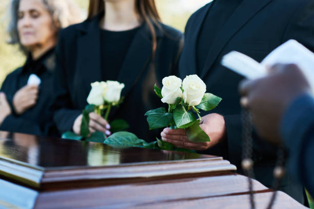 istock Focus on two fresh white roses held by man in black suit during funeral service 1674039324