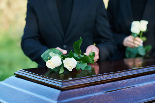 istock Focus on two fresh white roses being put on coffin lid by mature man 1674039334
