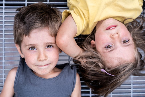portrait of twins boys and girls lying on a metal grate outdoor